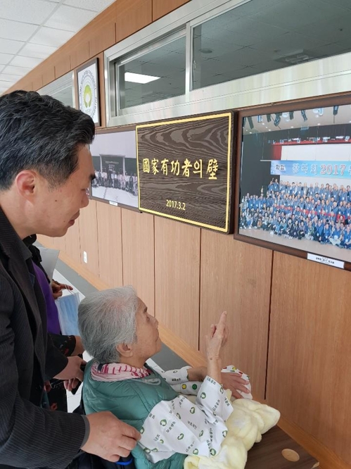 (서울=연합뉴스) 김종량 기자 = 투병 중인 오희옥 지사가 서울 중앙보훈병원 로비 '국가유공자의 벽'에 내걸린 '2017년 광복절 기념사진'에서 자신의 얼굴을 손가락으로 가리키고 있다. 그는 당시 91살의 나이로 세종문화회관에서 애국가를 독창했다.