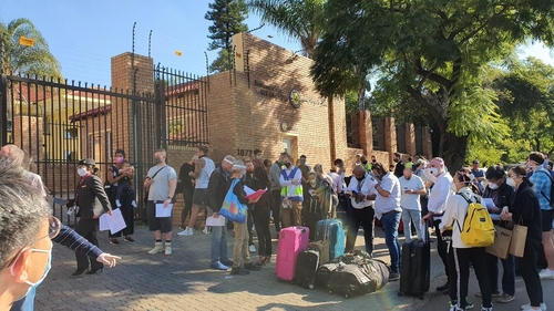 (요하네스버그=연합뉴스) 김성진 특파원 = 12일(현지시간) 남아공 프리토리아 주재 카타르 대사관 앞에 우리 교민 등 탑승객들이 공항 이동전 수속을 위해 대기하며 관련 사항을 체크하고 있다. sungjin@yna.co.kr