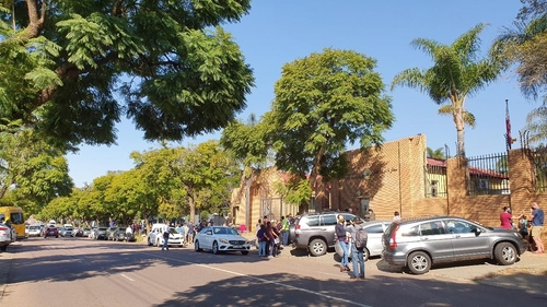 (요하네스버그=연합뉴스) 김성진 특파원 = 12일(현지시간) 남아공 프리토리아 주재 카타르 대사관 앞에 우리 교민 등 다국적 탑승객들이 공항 이동전 수속을 위해 도로변 차량과 함께 길게 줄을 서 있다. sungjin@yna.co.kr