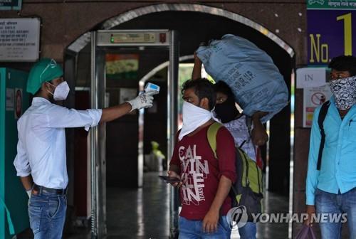 인도 뭄바이의 기차역에서 여행객의 체온을 재는 직원(왼쪽). [로이터=연합뉴스]