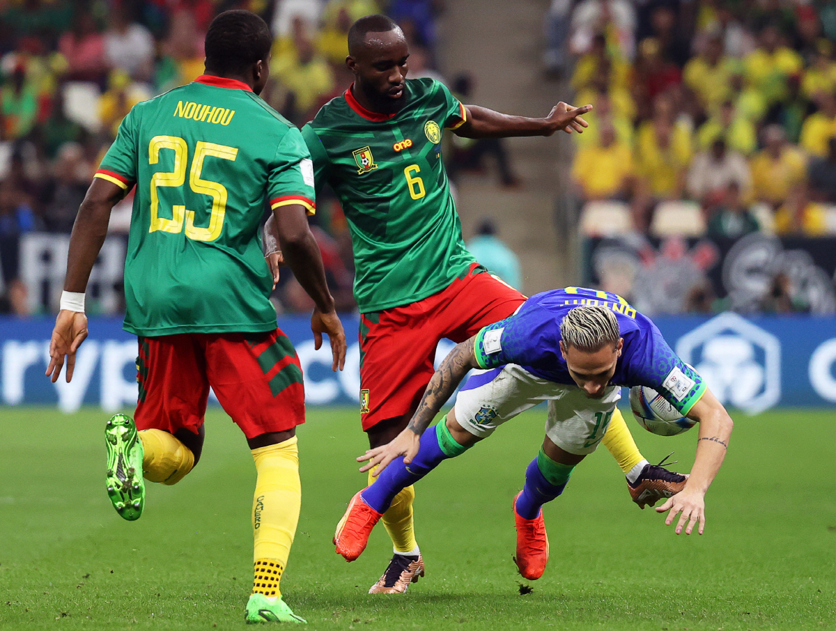 epa10345019 Antony (R) of Brazil in action against Nicolas Moumi Ngamaleu (C) of Cameroon during the FIFA World Cup 2022 group G soccer match between Cameroon and Brazil at Lusail Stadium in Lusail, Qatar, 02 December 2022. EPA/Abedin Taherkenareh