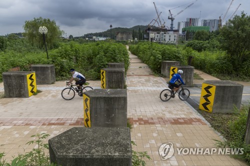 (고양=연합뉴스) 임병식 기자 = 24일 경기도 고양시 덕은동 대덕생태공원 내 용치공원에서 시민들이 용치 사이로 자전거를 타고 있다. 고양시는 정전 70주년을 맞아 전차 방해구조물인 '용치'를 활용해 전망대와 쉼터가 있는 공원을 조성했다. 2023.7.24 andphotodo@yna.co.kr