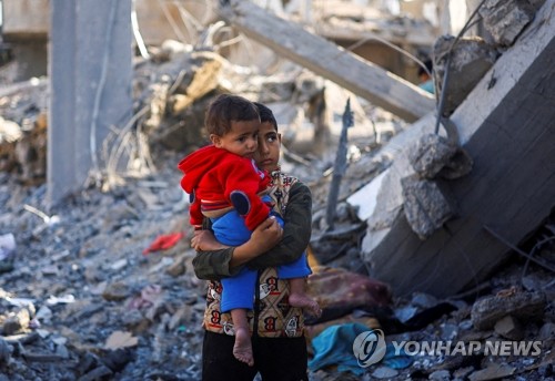 (라파 로이터=연합뉴스) 이스라엘과 팔레스타인 무장 정파 하마스 간 교전이 계속되는 가운데 4일(현지시간) 가자지구 남부 라파의 이스라엘 공습 현장에서 한 팔레스타인 소년이 아기를 안고 있다. 이날 요아브 갈란트 이스라엘 국방장관은 하마스 제거와 모든 인질의 귀환이라는 목표를 달성할 때까지 가자지구 남부에서 작전을 이어가겠다고 밝혔다. 2023.12.05 besthope@yna.co.kr