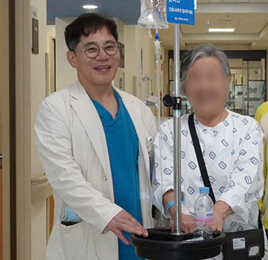 건강해진 환자와 함께 사진을 촬영하고 있는 장기육 교수(왼쪽).