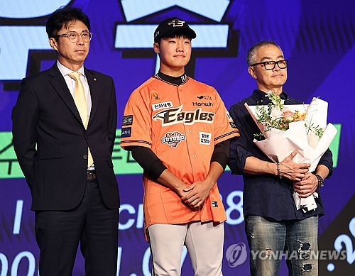 (서울=연합뉴스) 류영석 기자 = 11일 오후 서울 송파구 롯데호텔 월드 크리스탈볼룸에서 열린 2025 KBO 신인 드래프트에서 한화 이글스에 1라운드 2순위 지명을 받은 정우주(전주고)가 손혁 단장으로부터 유니폼을 받고 있다. 2024.9.11 ondol@yna.co.kr