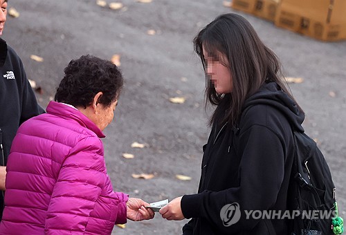 (강릉=연합뉴스) 유형재 기자 = 2025학년도 대학수학능력시험이 치러진 14일 강원 강릉시 제51지구 제5시험장인 강일여고에서 한 수험생을 응원 나온 할머니가 손녀에게 용돈을 건네며 격려하고 있다. 2024.11.14 yoo21@yna.co.kr