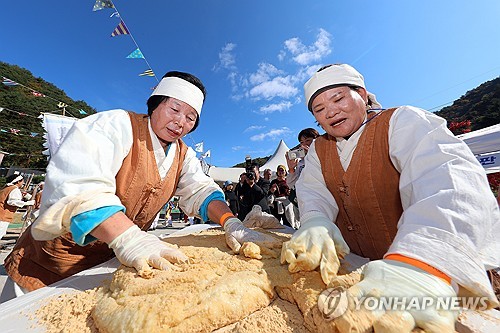 (인제=연합뉴스) 지난해 10월 26일 강원 인제군 인제읍 하추리 산촌에서 도리깨축제가 열려 주민들이 떡메치기 후 차진 반죽에 콩가루를 묻히며 인절미를 만들고 있다. [인제군 제공. 연합뉴스 자료사진]