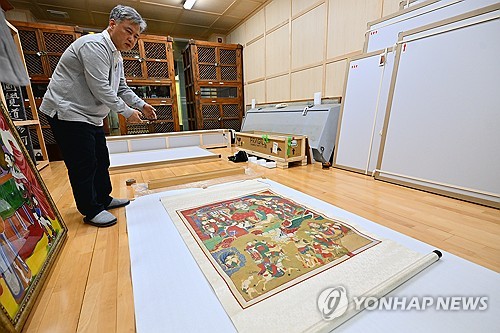 (속초=연합뉴스) 14일 강원 속초시 신흥사로 환지본처(還至本處·원래 있던 자리로 돌아옴)한 조선시대 '시왕도'(十王圖) 1점을 사찰 관계자가 살펴보고 있다. 2025.11.14 [속초시 제공. 재판매 및 DB 금지] ryu@yna.co.kr