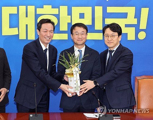 (서울=연합뉴스) 배재만 기자 = 더불어민주당 한병도 신임 원내대표(가운데)가 12일 국회에서 우상호 청와대 정무수석을 만나 이재명 대통령의 축하 난을 받고 있다. 오른쪽은 천준호 신임 원내운영수석부대표. 2026.1.12 scoop@yna.co.kr