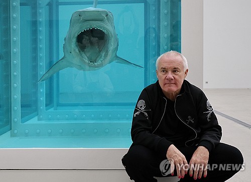 (서울=연합뉴스) 이재희 기자 = 영국 작가 데이미언 허스트가 18일 서울 종로구 국립현대미술관에서 열린 '진실은 없어 그러나 모든 것은 가능하지' 개인전에 전시된 대표작 '살아있는 자의 마음 속 죽음의 물리적 불가능성' 앞에서 포즈를 취하고 있다. 2026.3.18 scape@yna.co.kr