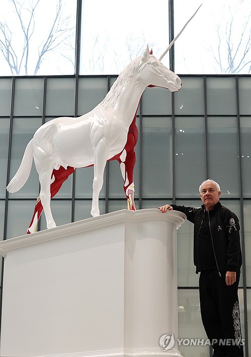 (서울=연합뉴스) 이재희 기자 = 영국 작가 데이미언 허스트가 18일 서울 종로구 국립현대미술관에서 열린 '진실은 없어 그러나 모든 것은 가능하지' 개인전에 전시된 '신화' 작품 앞에서 포즈를 취하고 있다. 2026.3.18 scape@yna.co.kr