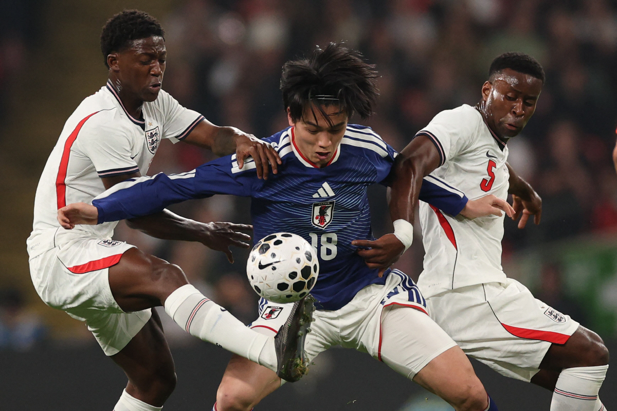 TOPSHOT - Japan's forward Ayase Ueda (C) vies with England's midfielder Kobbie Mainoo (L) and England's defender Marc Guehi (R) during the friendly international football match between England and Japan at Wembley Stadium in London on March 31, 2026. (Photo by Adrian Dennis / AFP) / NOT FOR MARKETING OR ADVERTISING USE / RESTRICTED TO EDITORIAL USE