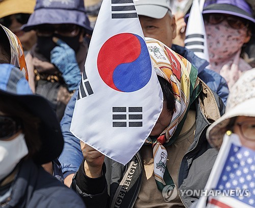 (서울=연합뉴스) 황광모 기자 = 헌법재판소가 윤석열 전 대통령의 파면을 선고한 4일 서울 용산구 한남동 대통령 관저 인근에서 열린 대한민국바로세우기국민운동본부 탄핵 반대 집회 참석자가 문형배 헌재 소장 권한대행의 파면 결정 주문을 확인한 뒤 태극기를 들고 안타까워하고 있다. 2025.4.4 hkmpooh@yna.co.kr