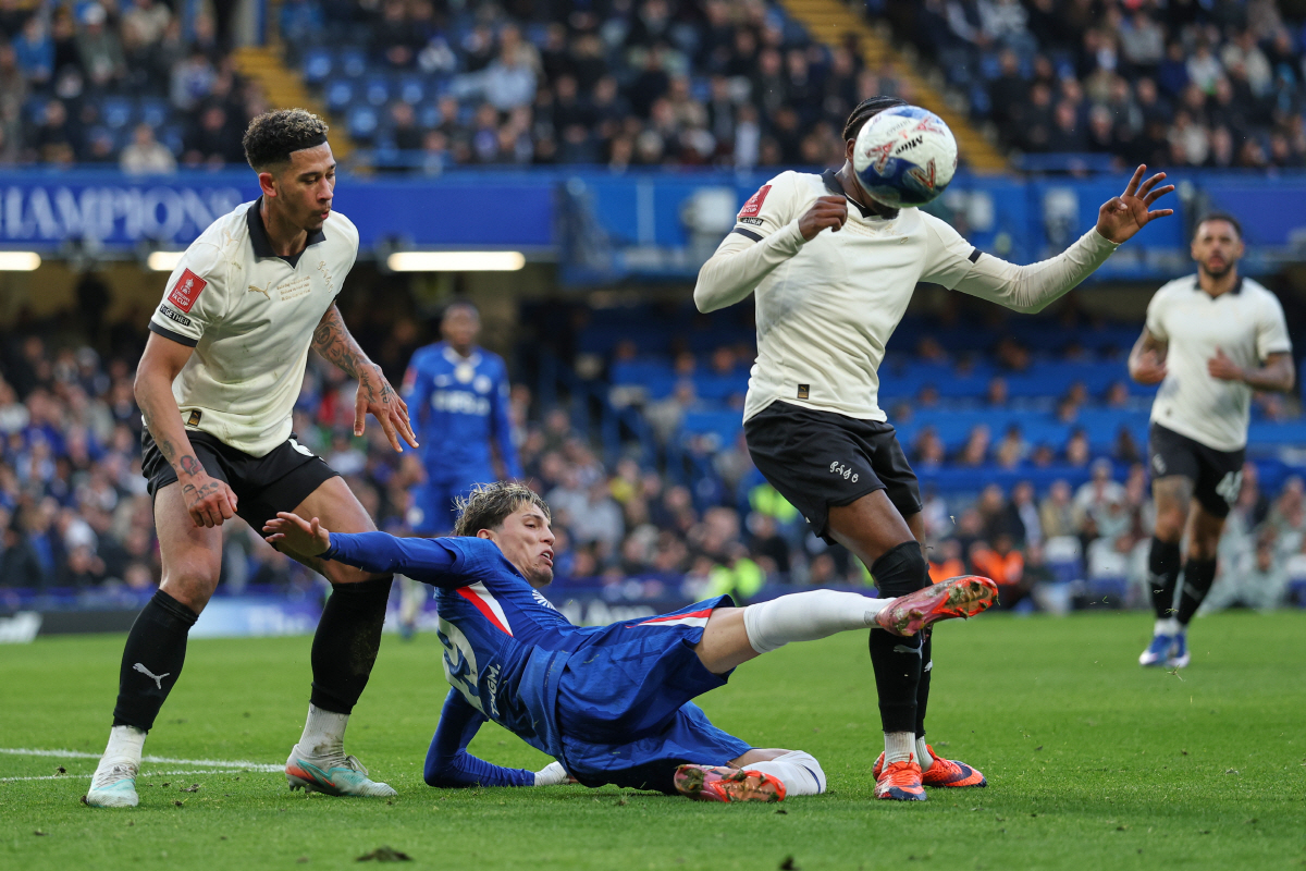 Chelsea's Alejandro Garnacho, centre, challenges for the ball with Port Vale's Jordan Lawrence-Gabriel, left, and Port Vale's Ethon Archer during the English FA Cup quarterfinal soccer match between Chelsea and Port Vale in London, England, Saturday, April 4, 2026. (AP Photo/Ian Walton)