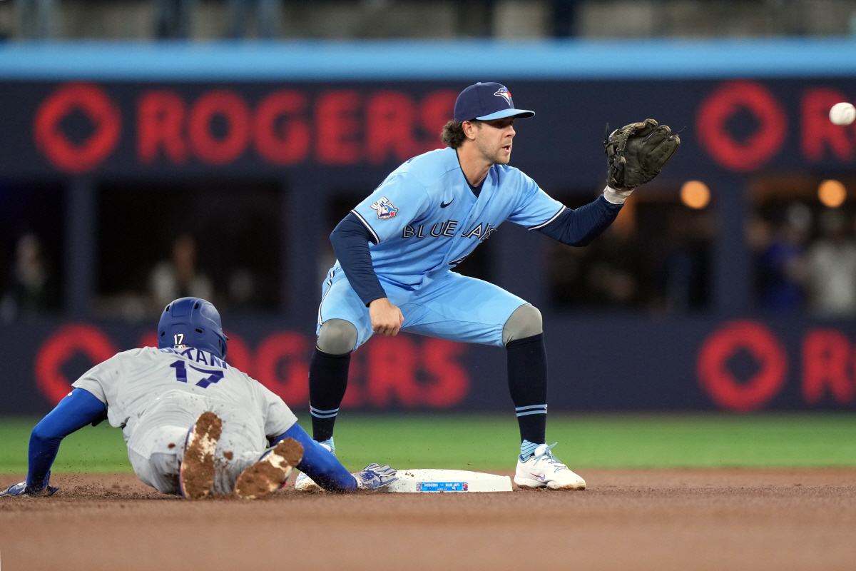 Los Angeles Dodgers' Shohei Ohtani (17) gets back to the base as Toronto Blue Jays third baseman Ernie Clement (22) reaches for the throw during the first inning of a baseball game in Toronto, Wednesday, April 8, 2026. (Nathan Denette/The Canadian Press via AP) MANDATORY CREDIT