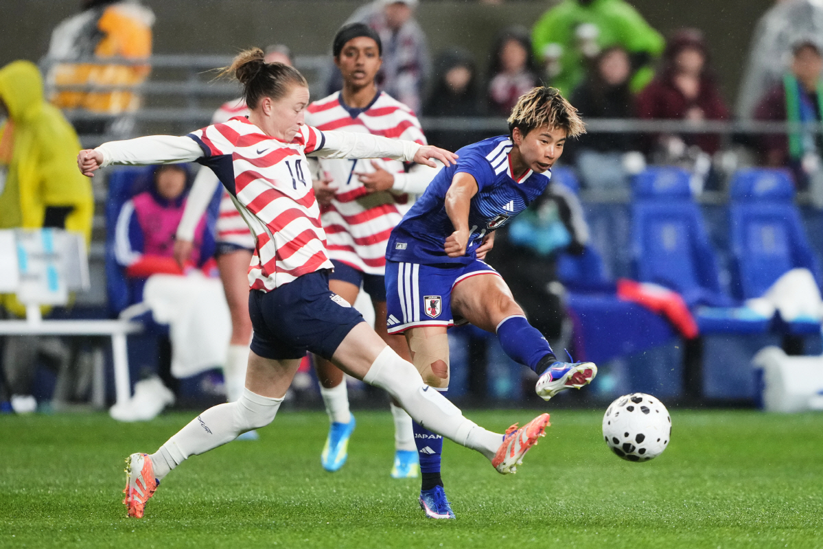 Japan forward Mina Tanaka, right, chips the ball past United States defender Emily Sonnett, left, during the second half of an international friendly soccer match Tuesday, April 14, 2026, in Seattle. (AP Photo/Lindsey Wasson)