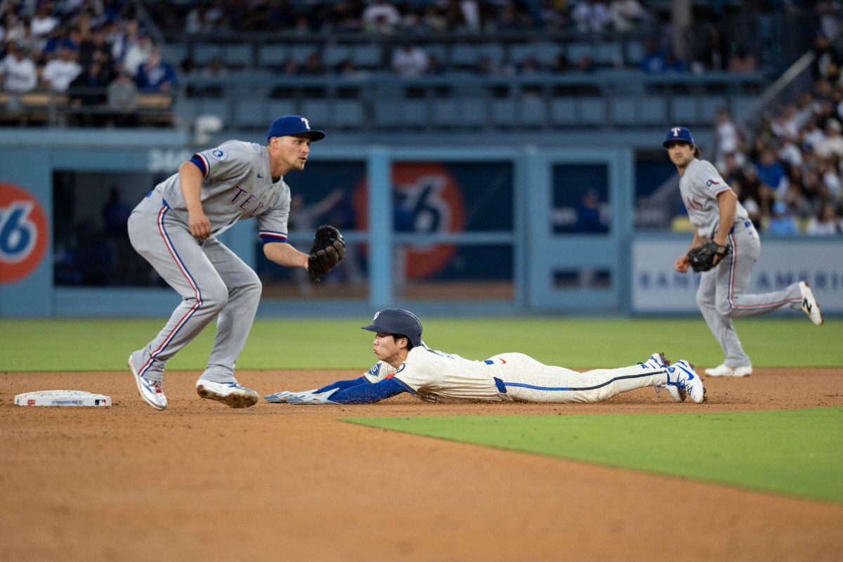 Los Angeles Dodgers' Hyeseong Kim, center, steals second base during the fourth inning of a baseball game against the Texas Rangers in Los Angeles, Saturday, April 11, 2026. (AP Photo/Kyusung Gong)