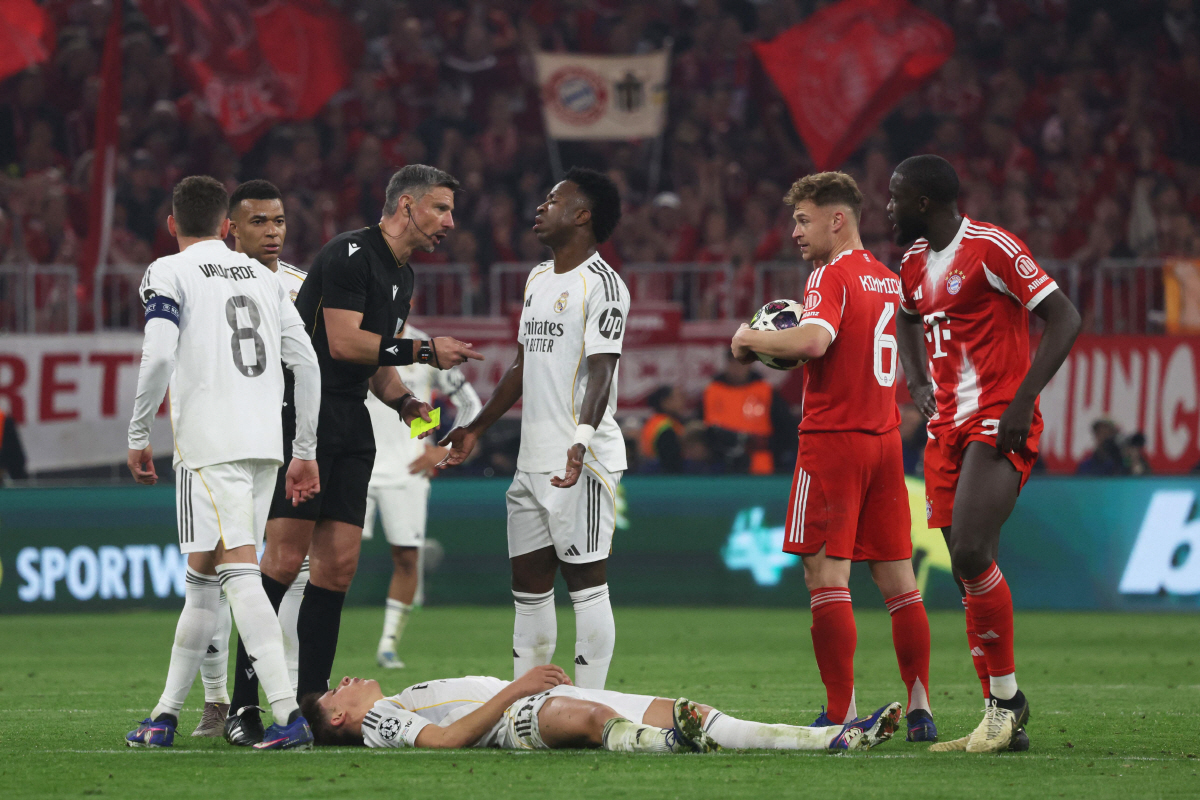 Real Madrid's Turkish midfielder #15 Arda Guler reacts on the ground as Real Madrid's Brazilian forward #07 Vinicius Junior (C) argues with the referee during the UEFA Champions League quarter-final second leg football match between FC Bayern Munich and Real Madrid in Munich, southern Germany, on April 15, 2026. (Photo by Karl-Josef HILDENBRAND / AFP)