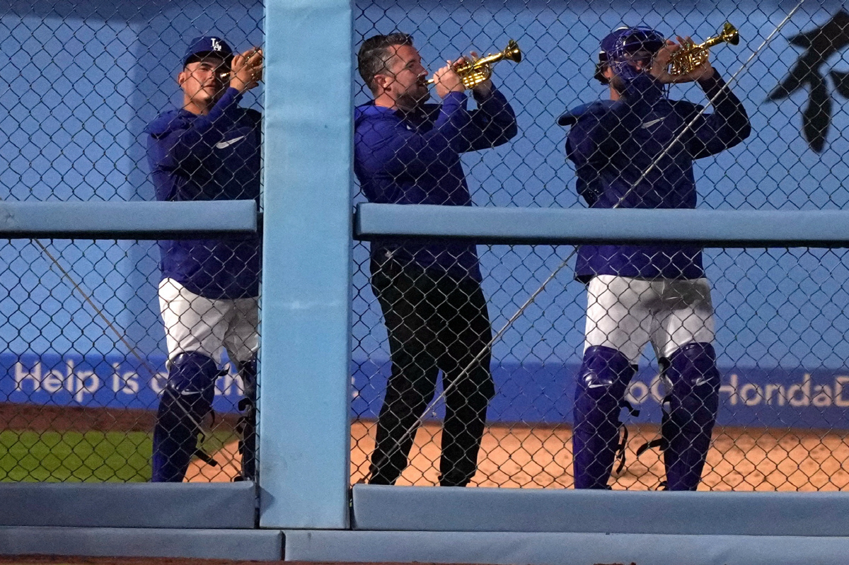 Members of the Los Angeles Dodgers play toy trumpets in the bullpen as pitcher Edwin Diaz takes the field during the ninth inning of a baseball game against the Texas Rangers, Friday, April 10, 2026, in Los Angeles. (AP Photo/Mark J. Terrill)