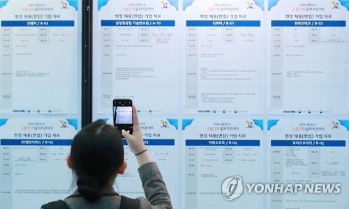 2019년 3월 '2019 대한민국 고졸인재 일자리 콘서트'를 찾은 한 취업준비생이 채용정보 게시판을 살펴보던 중 현장 채용 기업 자료를 사진으로 찍고 있다. [연합뉴스 자료사진]