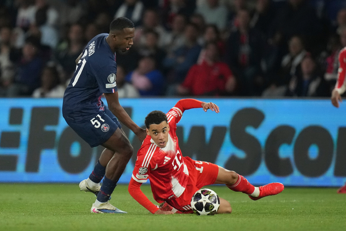 Bayern's Jamal Musiala, bottom, and PSG's Willian Pacho challenge for the ball during the Champions League semifinal first leg soccer match between Paris Saint-Germain and Bayern Munich in Paris, Tuesday, April 28, 2026. (AP Photo/Christophe Ena)