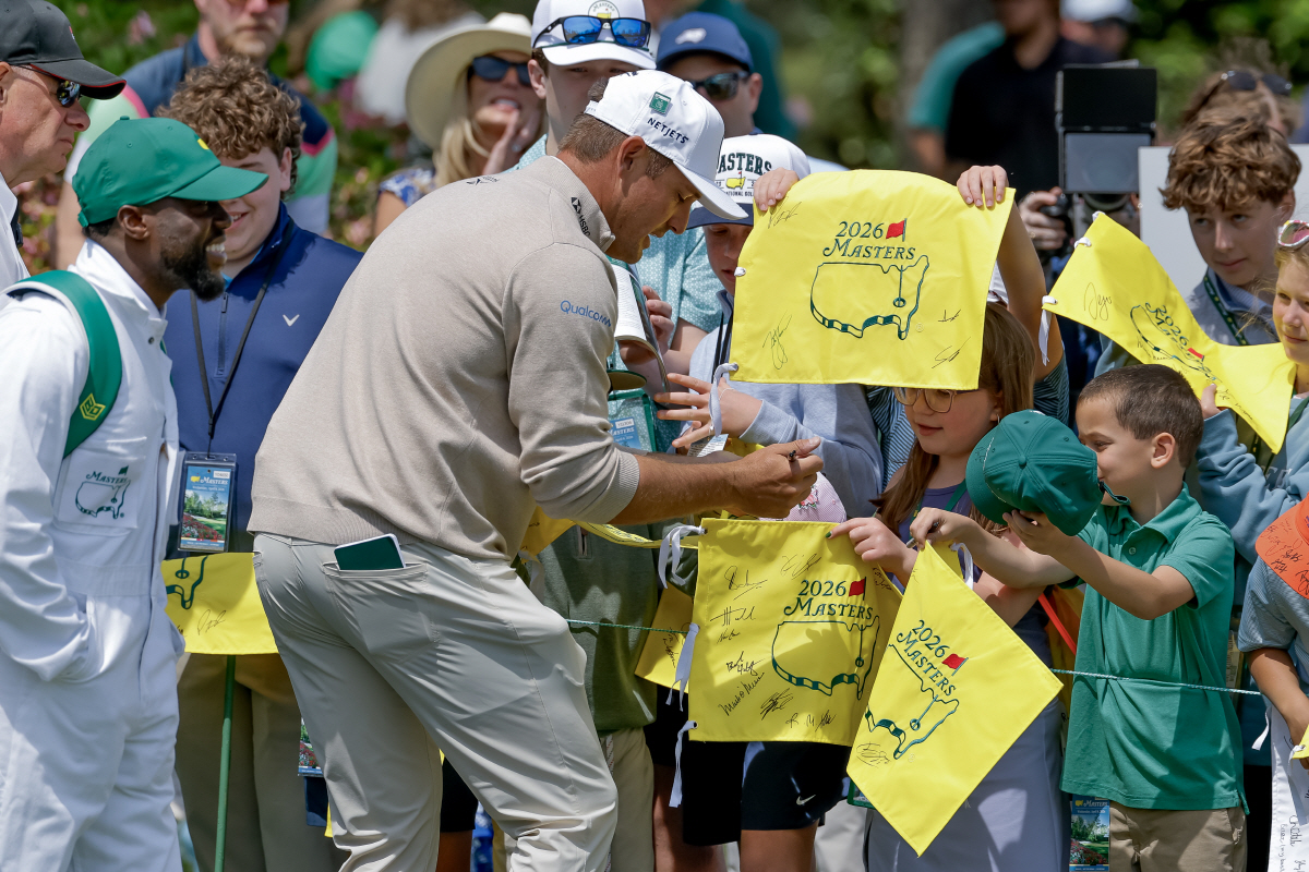 epa12876314 Bryson DeChambeau (R) of the US signs autographs for young patrons as his caddie, comedian Kevin Hart (L) looks on during the Par 3 Contest during the 2026 Masters Tournament at the Augusta National Golf Club in Augusta, Georgia, USA, 08 April 2026. The Masters golf tournament begins 09 April 2026. EPA/ERIK S. LESSER