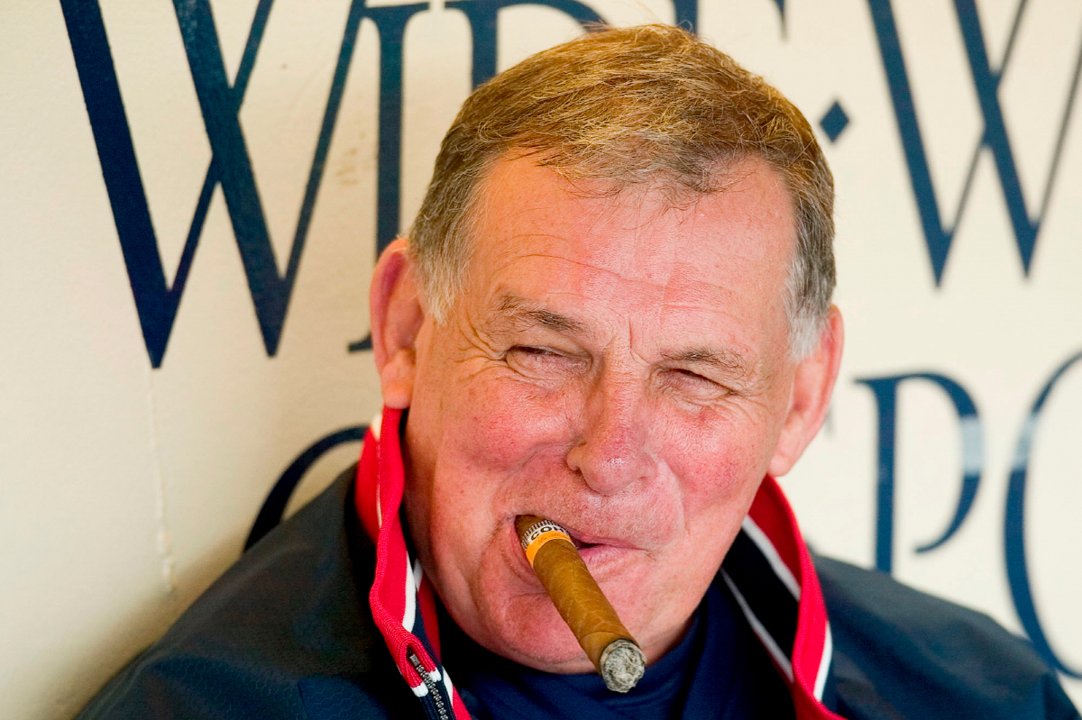 FILE - Atlanta Braves manager Bobby Cox smiles while smoking a cigar in the dugout with his coaching staff before the start of workouts Feb. 22, 2004, in Lake Buena Vista, Fla. (AP Photo/Scott Audette, File) FILE PHOTO