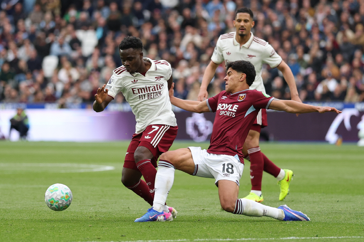 West Ham's Mateus Fernandes tackles Arsenal's Bukayo Saka during the Premier League soccer match between West Ham and Arsenal in London, Sunday, May 10, 2026. (AP Photo/Ian Walton)