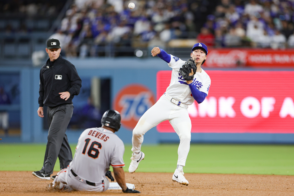 Los Angeles Dodgers second baseman Hyeseong Kim, right, attempts to throw out San Francisco Giants' Heliot Ramos at first after forcing out Rafael Devers during the fourth inning of a baseball game Thursday, May 14, 2026, in Los Angeles. (AP Photo/Ryan Sun)