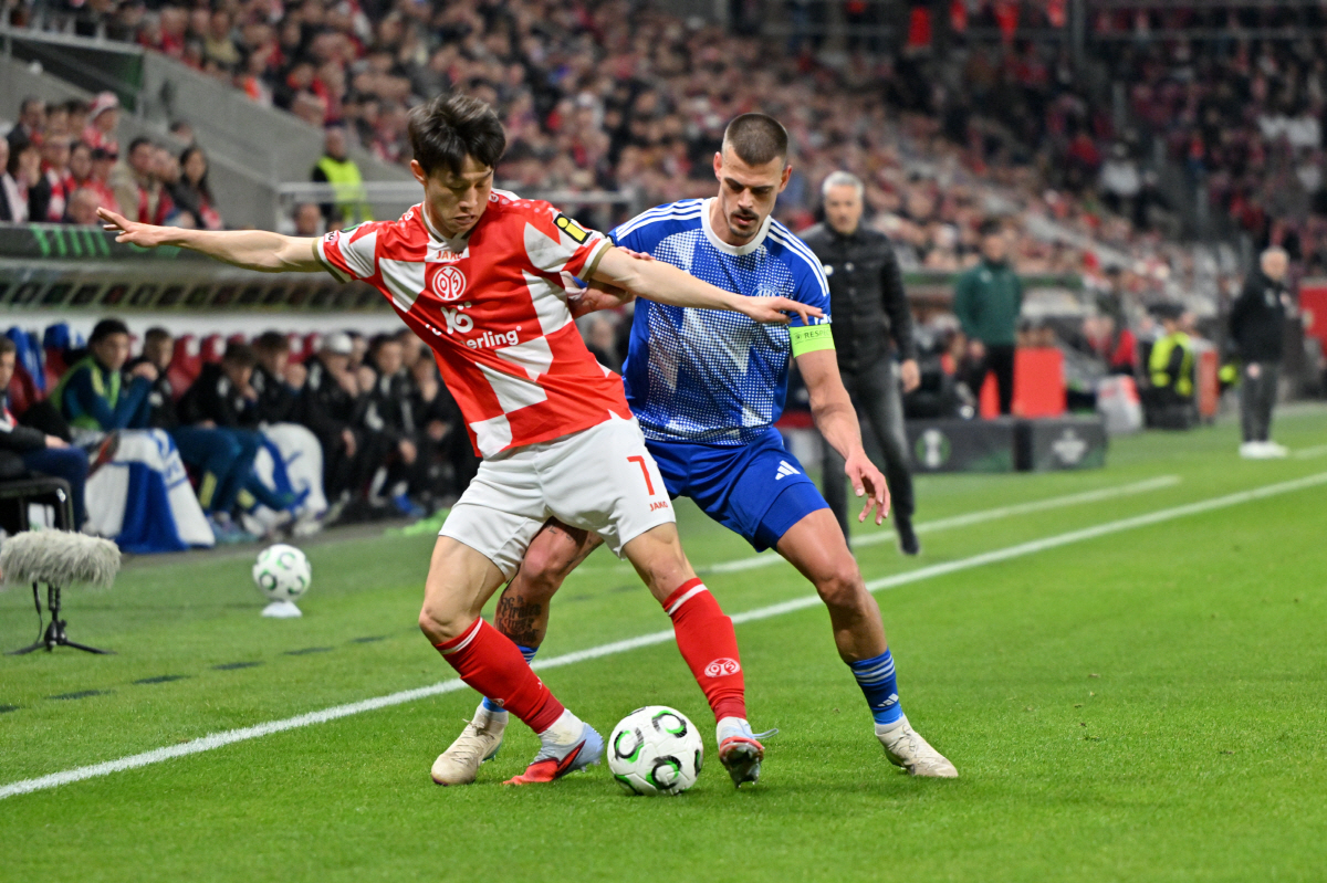 Sigma's Jan Kliment, right, and Mainz' Jae-sung Lee, left, challenge for the ball during the Conference League round of sixteen second leg soccer match between FSV Mainz 05 and SK Sigma Olomouc in Mainz, Germany, Thursday, March 19, 2026. (Torsten Silz/dpa via AP) THE DEUTSCHE FUSSBALL LIGA DFL DOES NOT ALLOW ITS IMAGES TO BE USED AS SEQUENCES TO EMULATE VIDEO; GERMANY OUT; MANDATORY CREDIT
