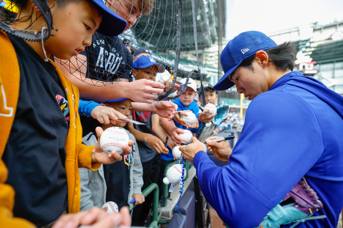 Los Angeles Dodgers shortstop Hyeseong Kim (6) signs autographs for fans before a baseball game against the Milwaukee Brewers, Saturday, May 23, 2026, in Milwaukee. (AP Photo/Jeffrey Phelps)
