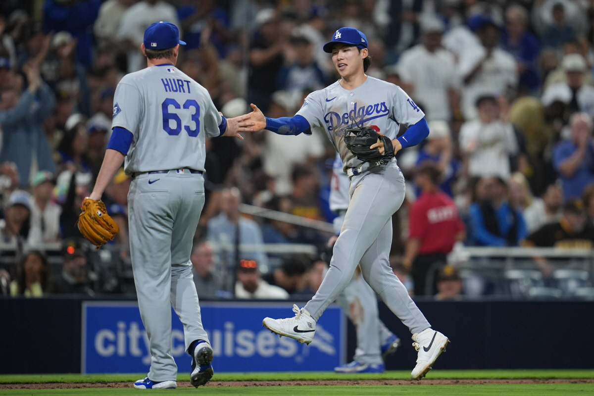 Los Angeles Dodgers second baseman Hyeseong Kim, right, celebrates with pitcher Kyle Hurt (63) after turning a double play during the eighth inning of a baseball game against the San Diego Padres Wednesday, May 20, 2026, in San Diego. San Diego Padres' Fernando Tatis Jr. was out at second and Miguel Andujar at first on the play. (AP Photo/Gregory Bull)