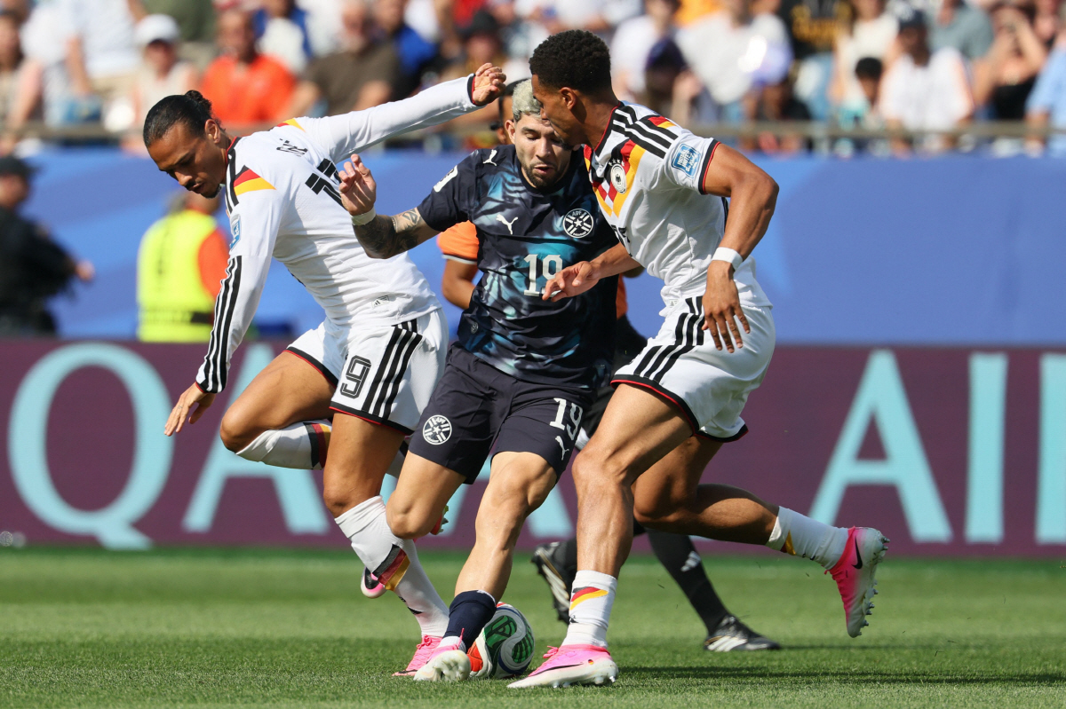 Germany's forward #19 Leroy Sane (L) and Paraguay's midfielder #19 Julio Enciso (C) fight for the ball during the 2026 World Cup round of 32 football match between Germany and Paraguay at the Boston Stadium in Foxborough on June 29, 2026. (Photo by Odd ANDERSEN / AFP)