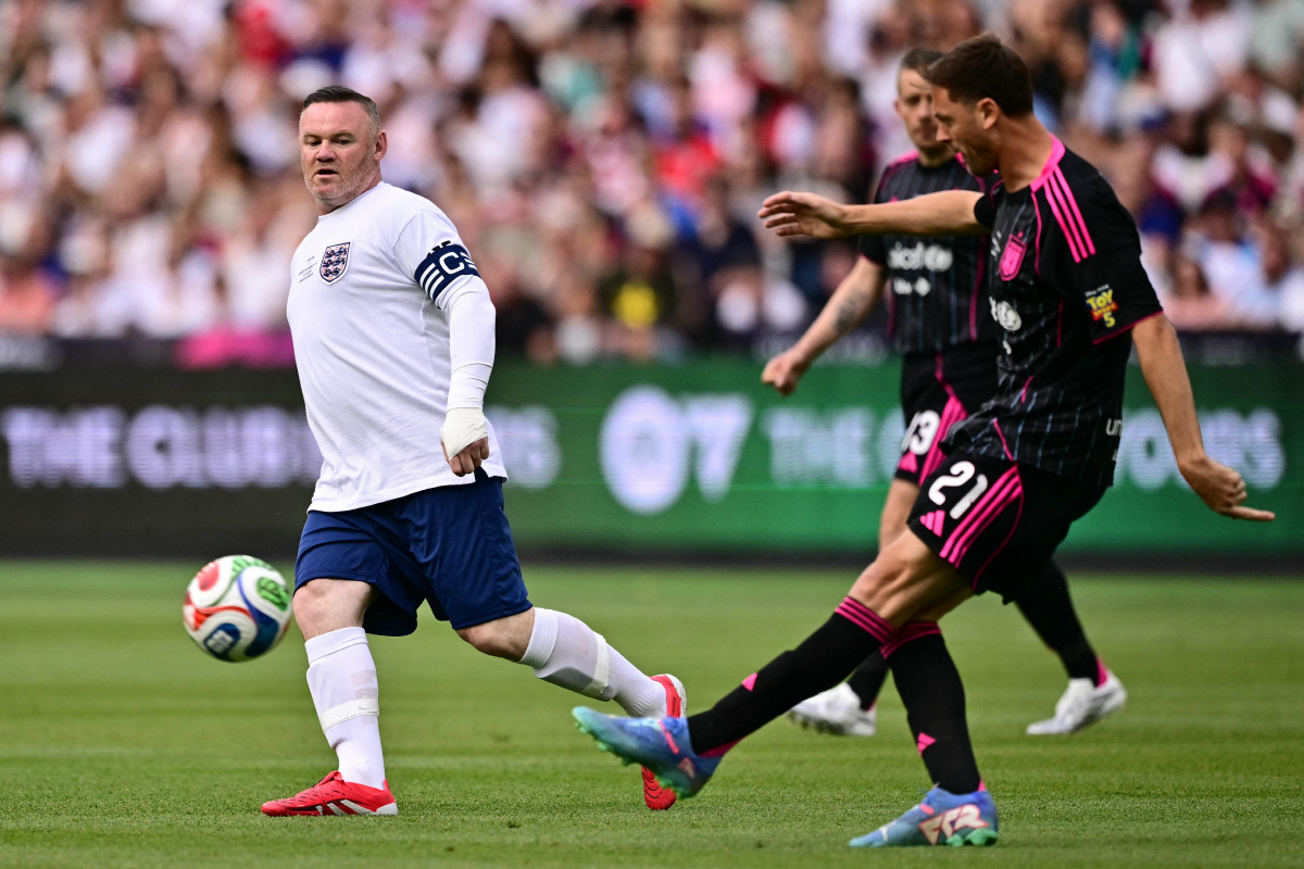 Serbian former footballer Nemanja Matic (R) clears under pressure from British former footballer Wayne Rooney (L) during the England XI v World XI charity football match for Soccer Aid for Unicef at the London Stadium, in east London on May 31, 2026. (Photo by Ben STANSALL / AFP)