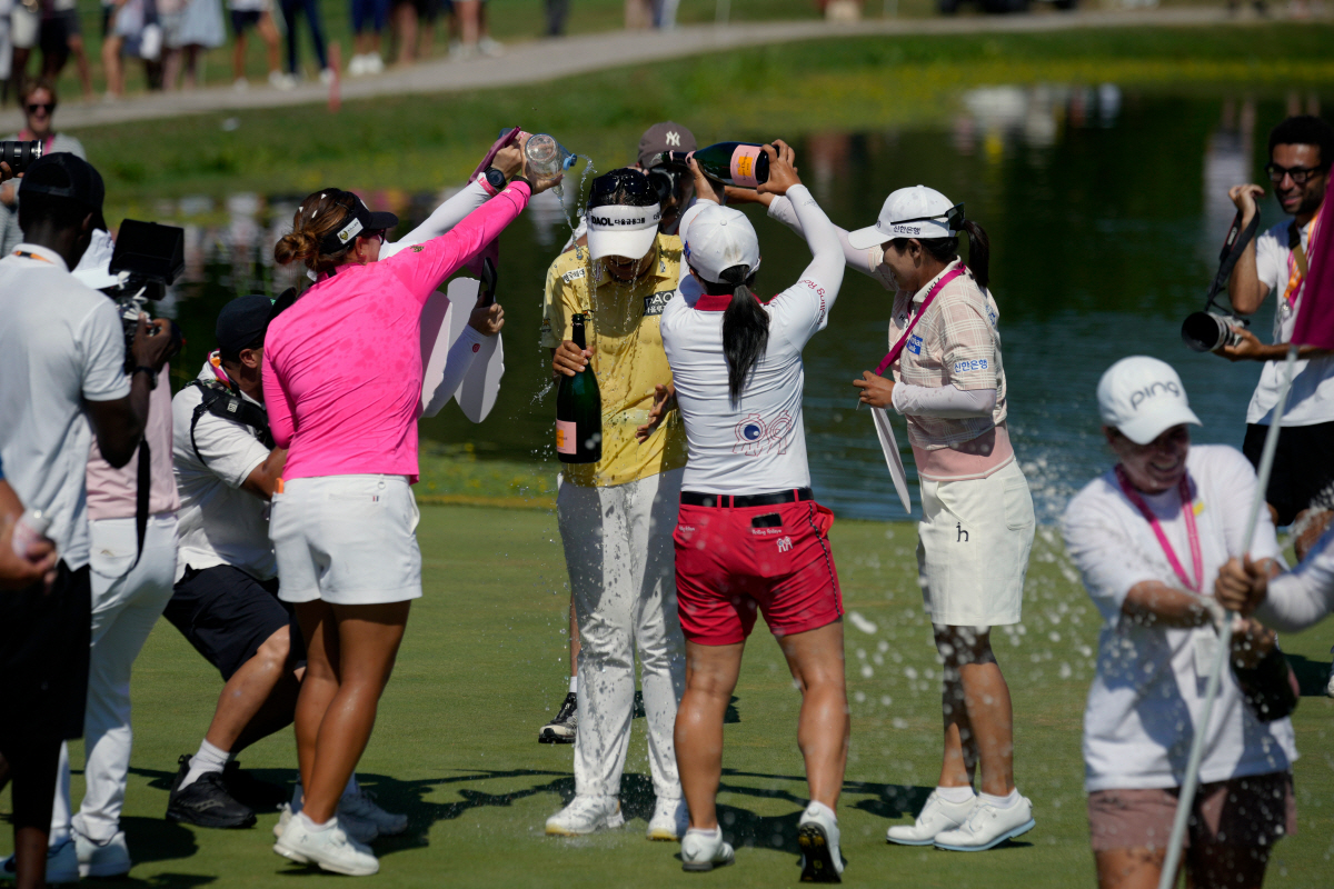 Haeran Ryu, of South Korea, celebrates with her teammates after winning the Evian Championship women's golf tournament, in Evian, eastern France, Sunday, July 12, 2026. (AP Photo/Laurent Cipriani)