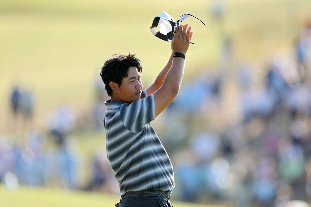 SOUTHAMPTON, NEW YORK - JUNE 21: Tom Kim of Republic of Korea acknowledges the crowd on the 18th green after finishing his round during the final round of the 126th U.S. OPEN at Shinnecock Hills Golf Club on June 21, 2026 in Southampton, New York. Kate McShane/Getty Images/AFP (Photo by Kate McShane / GETTY IMAGES NORTH AMERICA / Getty Images via AFP)