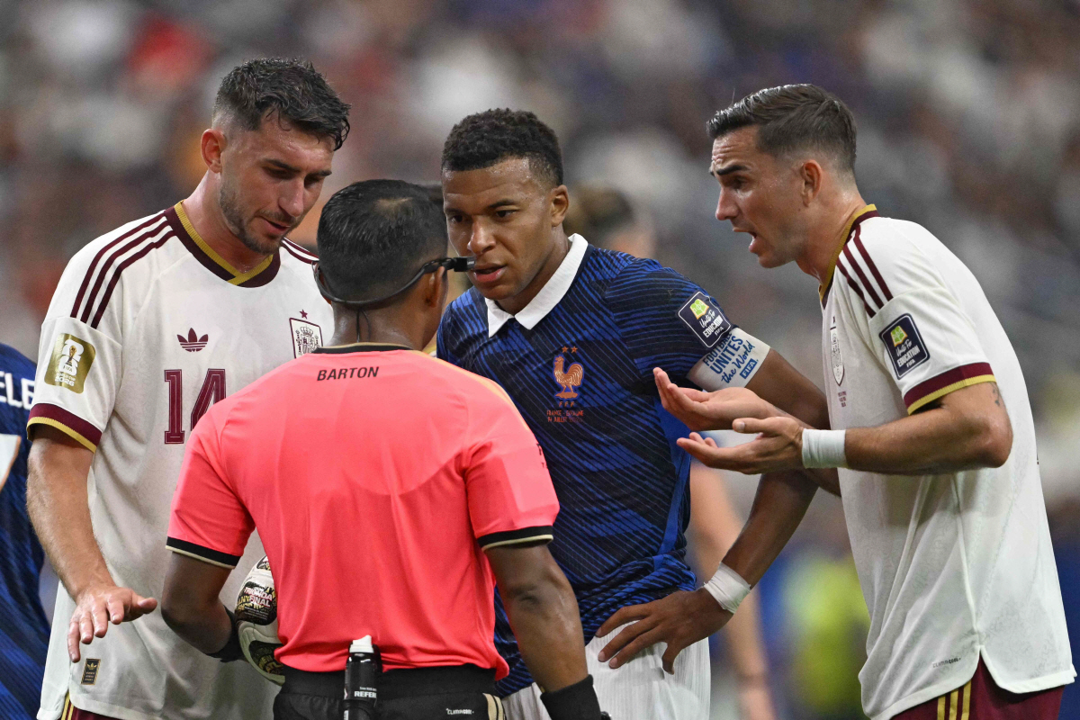 France's forward #10 Kylian Mbappe (C), Spain's defender #14 Aymeric Laporte (L) and Spain's midfielder #08 Fabian Ruiz (R) talk with Salvadoran referee Ivan Barton during the 2026 World Cup football tournament semi-final match between France and Spain at the Dallas Stadium in Arlington on July 14, 2026. (Photo by MAURO PIMENTEL / AFP)